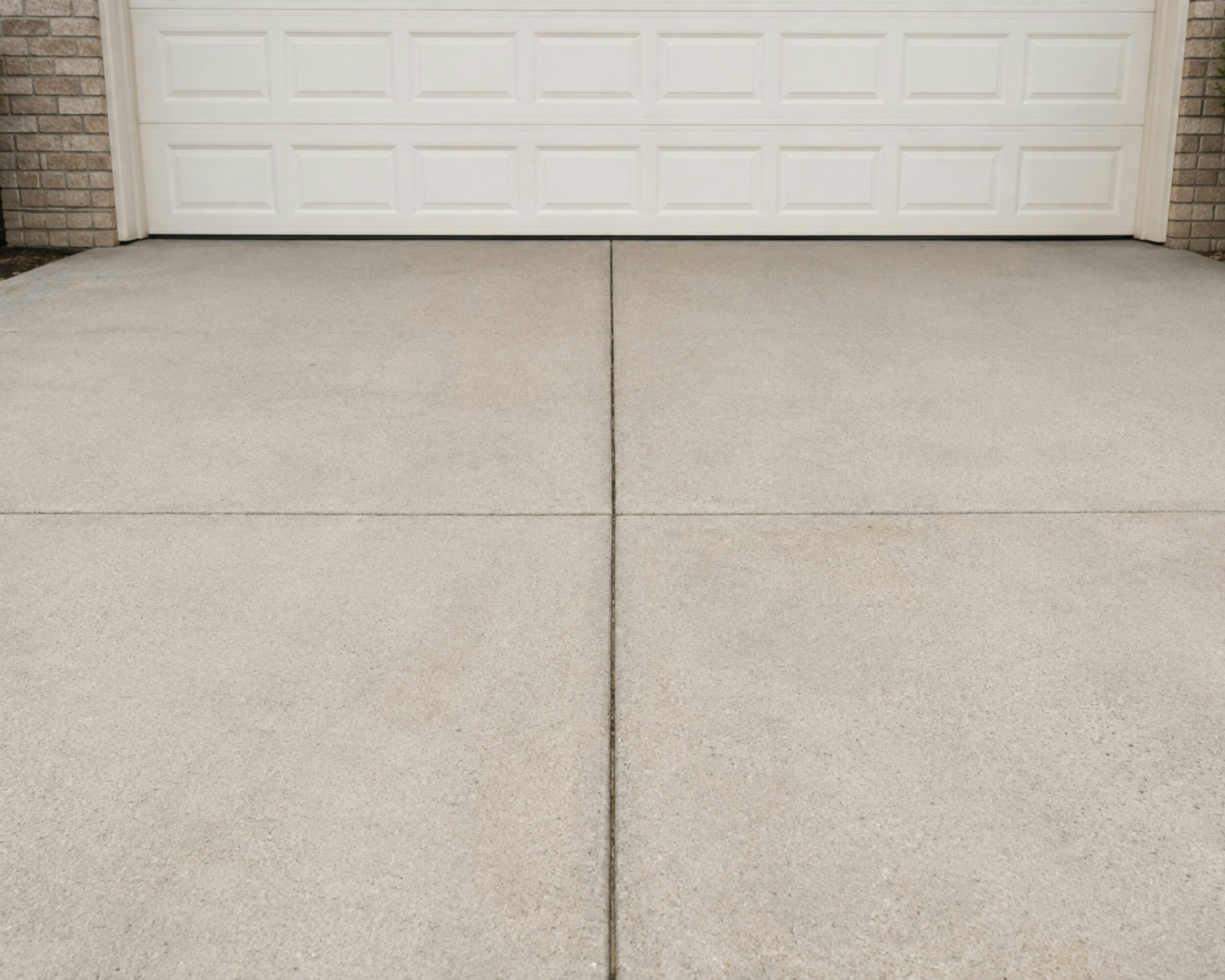 A freshly poured concrete driveway in front of a white garage door