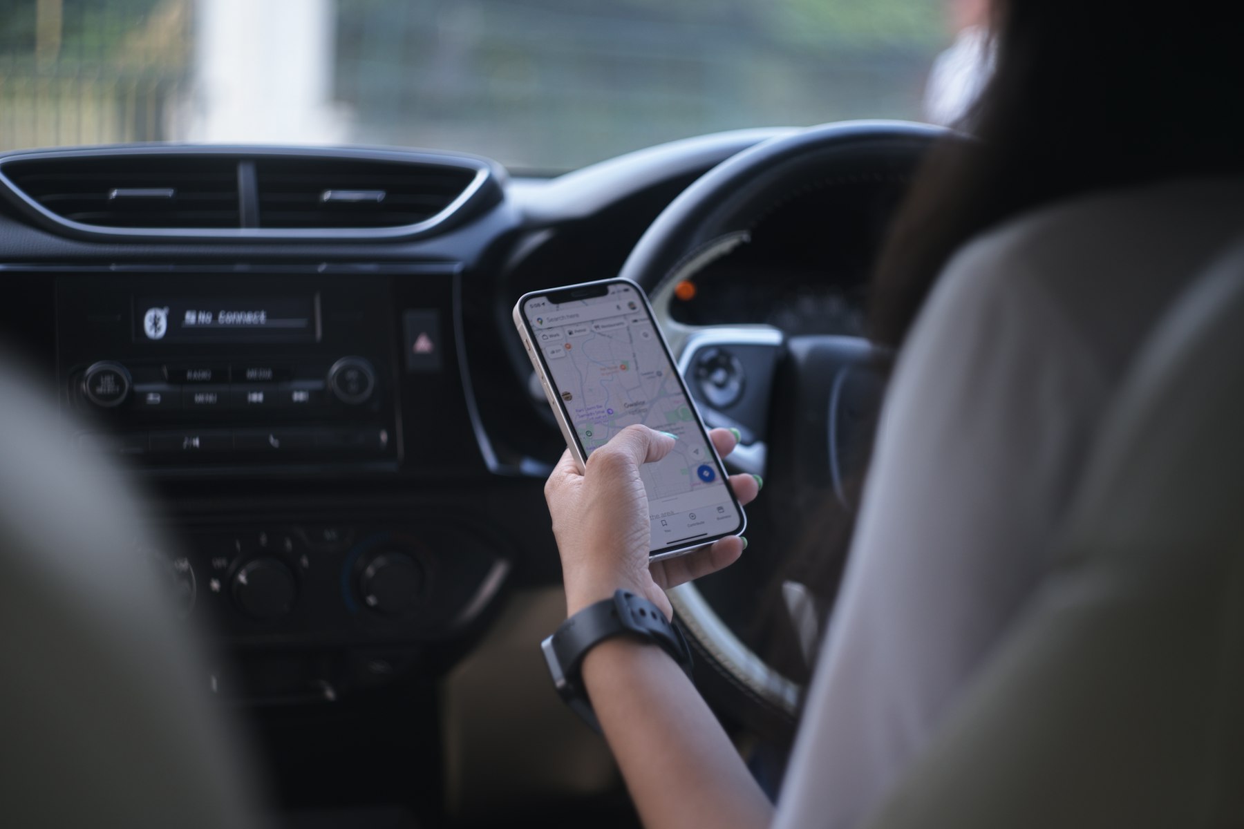 A person checking a navigation app on their phone while sitting in a car