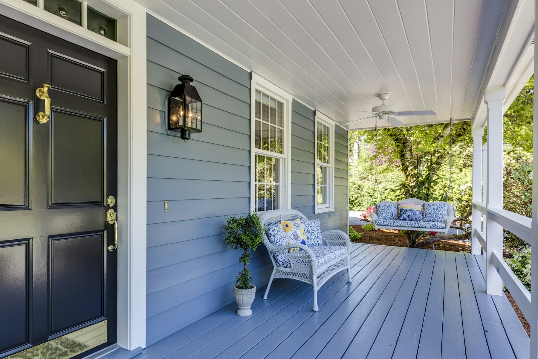 A freshly painted porch with blue-gray siding and crisp white trim on a suburban home