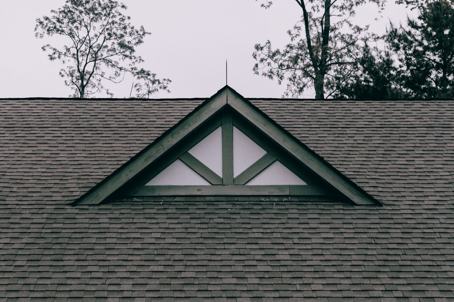 A residential asphalt shingle roof with a gable window