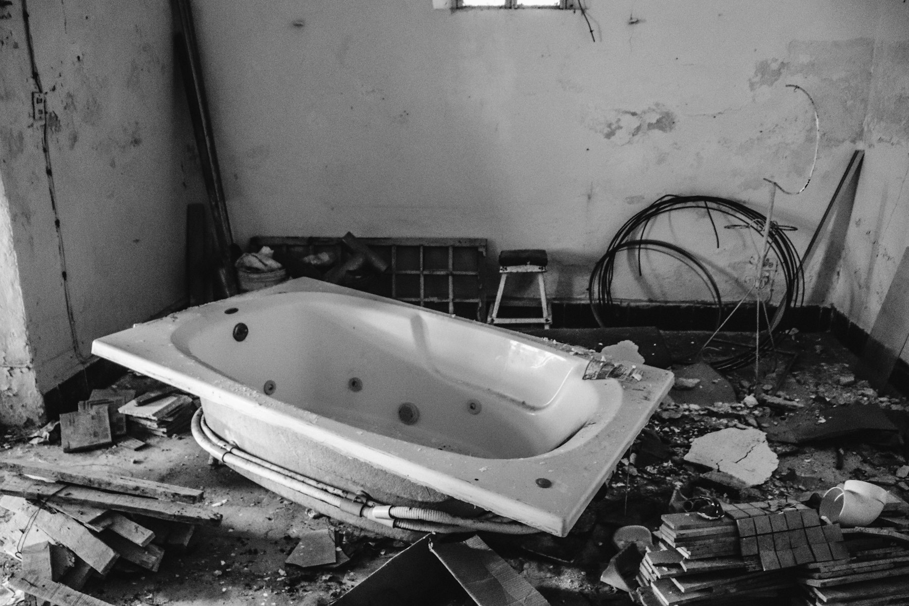 A water-damaged bathroom interior with peeling walls and debris on the floor