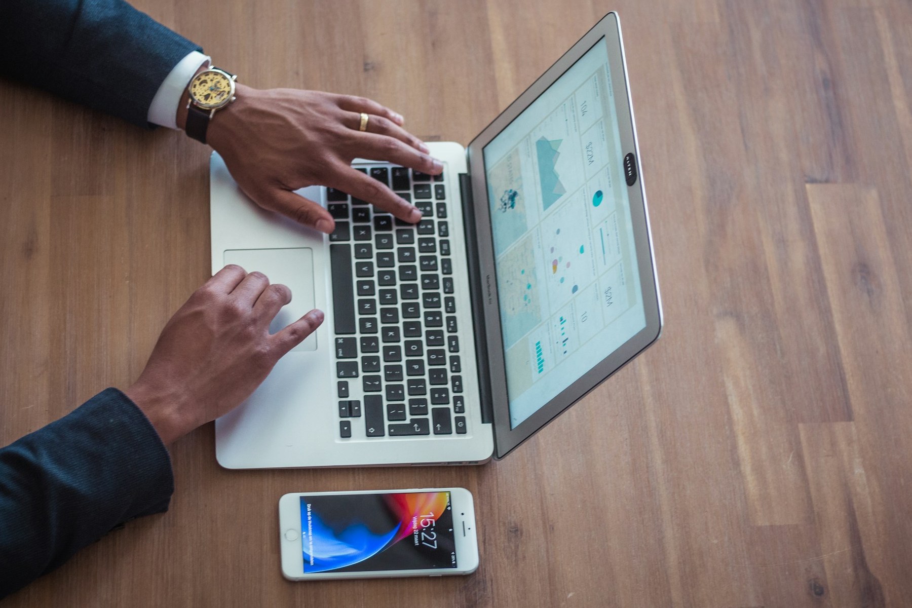 A laptop showing a map beside a phone on a wooden desk