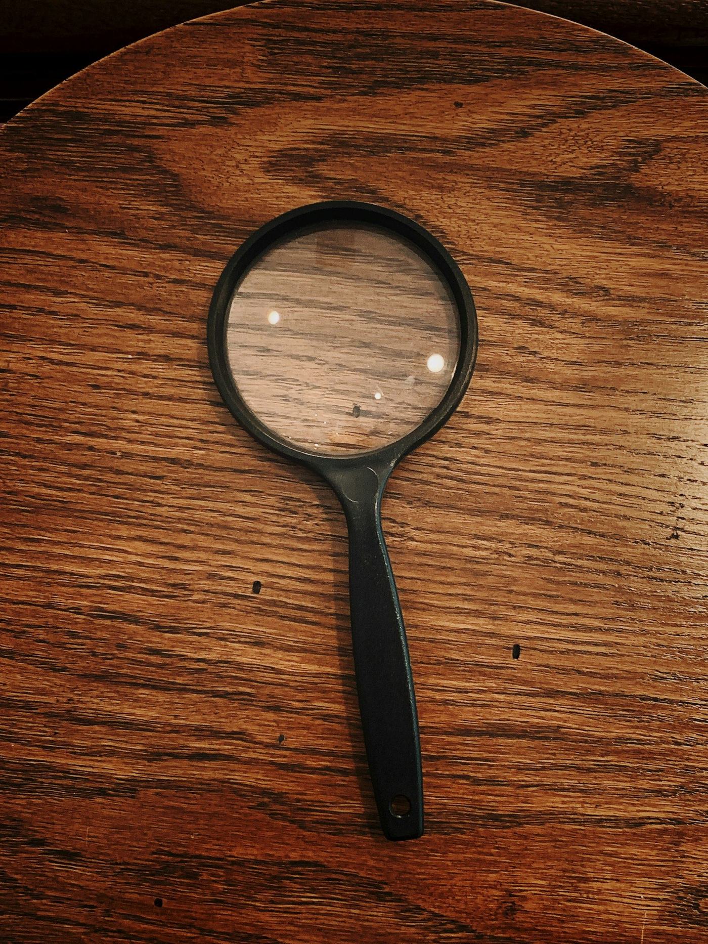 A vintage magnifying glass resting on a wood-grain desk