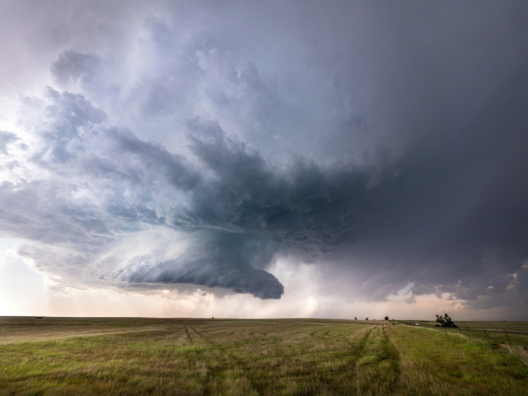 A dramatic supercell storm cloud over an open Great Plains field