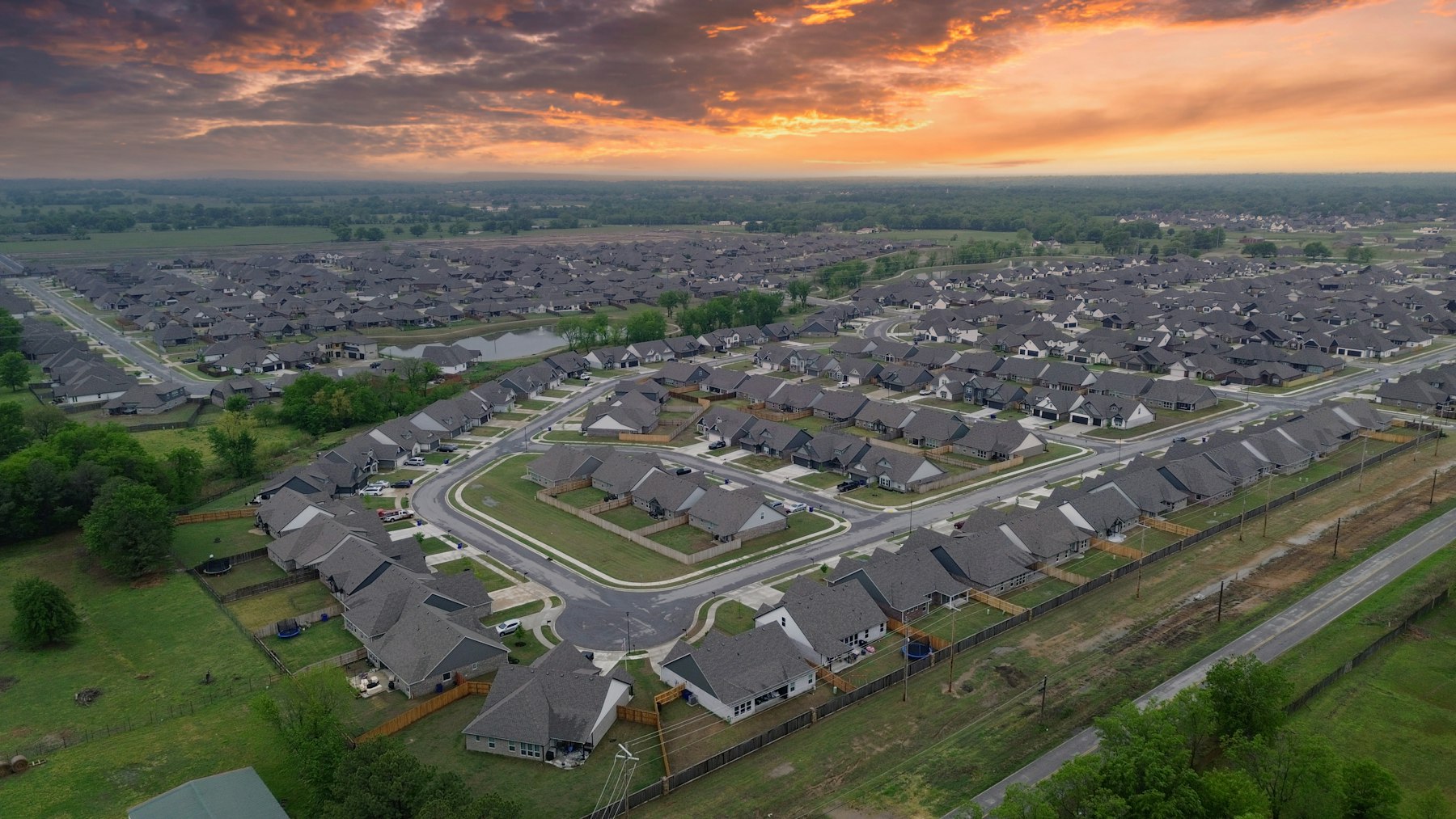 Aerial view of a Tulsa-area neighborhood at sunset, showing distinct zones of the city