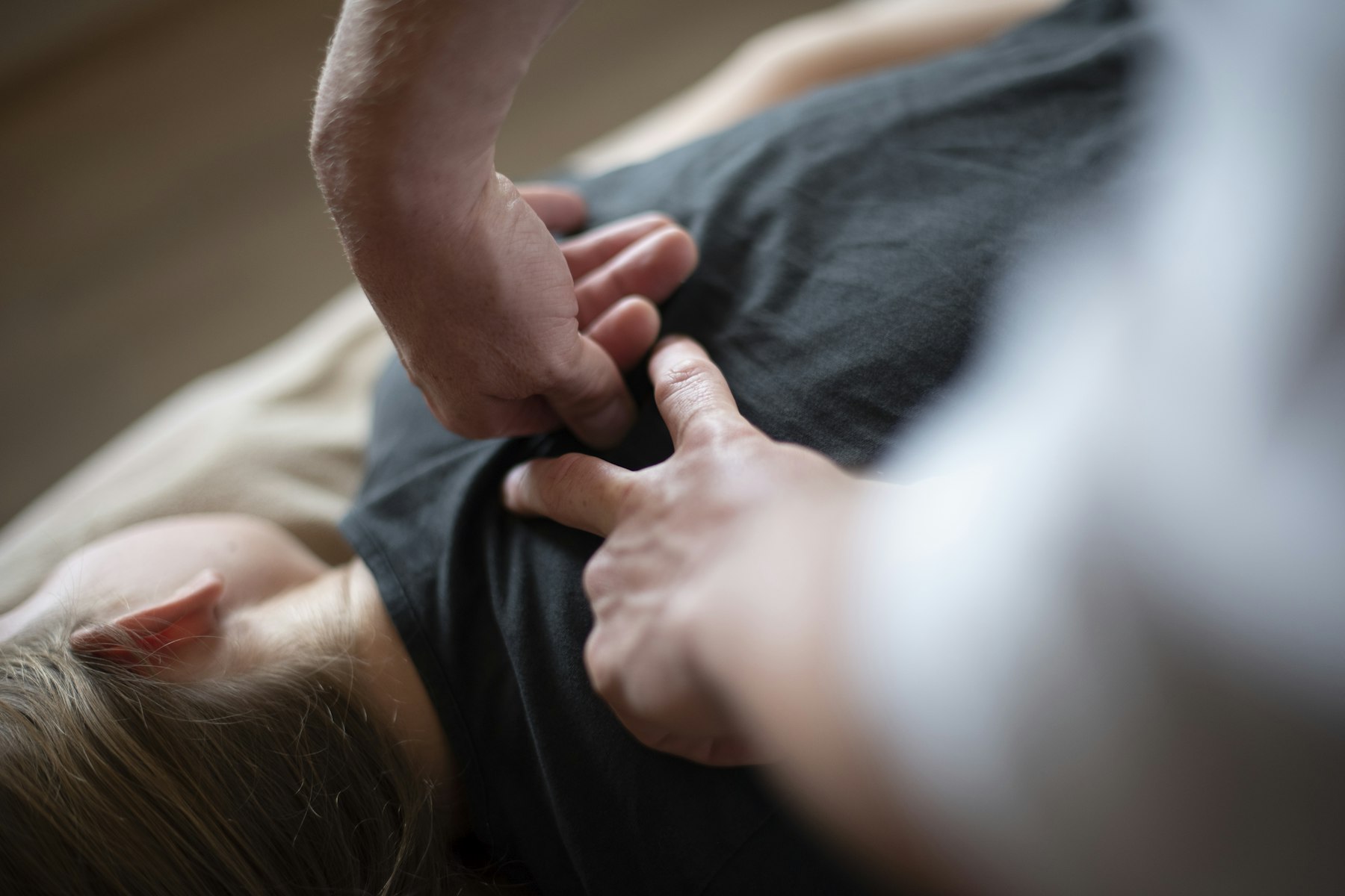 A chiropractor's hands working on a patient's upper back