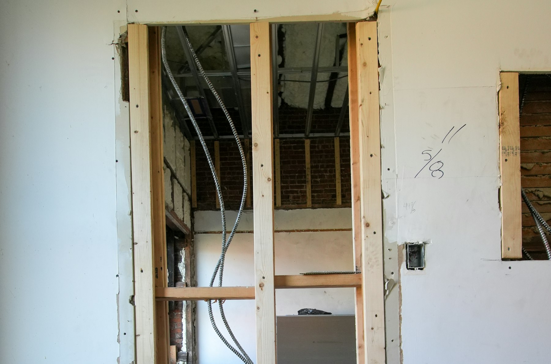 A framed doorway in an unfinished house with electrical conduit running up into the ceiling