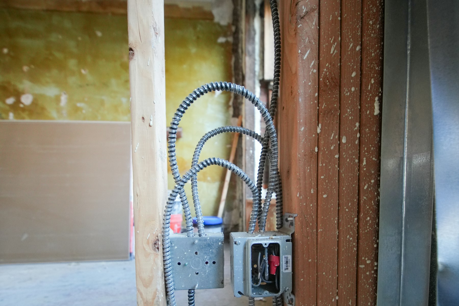 Flexible conduit and junction boxes running through an unfinished stud wall