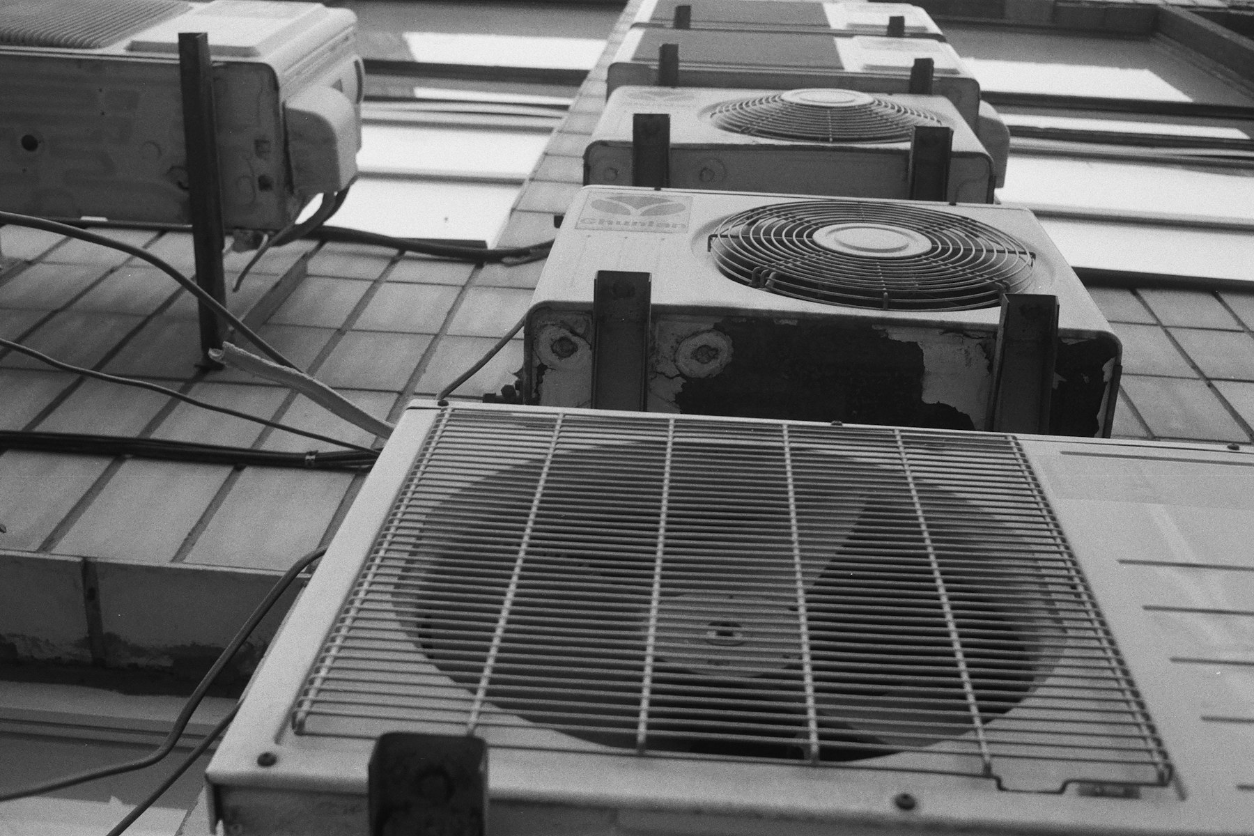 A row of rooftop HVAC condenser units viewed from below